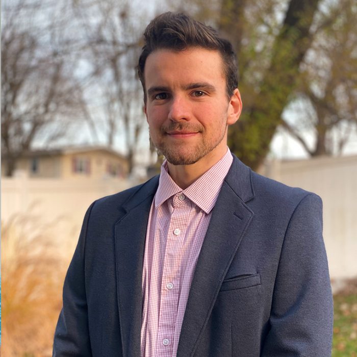 Brandon Pokedoff, Advertising Specialist, in a charcoal suit and pink button down