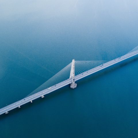 aerial view of a modern suspension bridge spanning blue water
